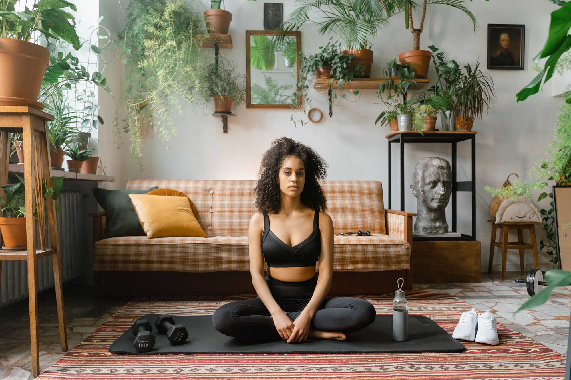 Woman sitting on a yoga mat in a cross-legged position to meditate