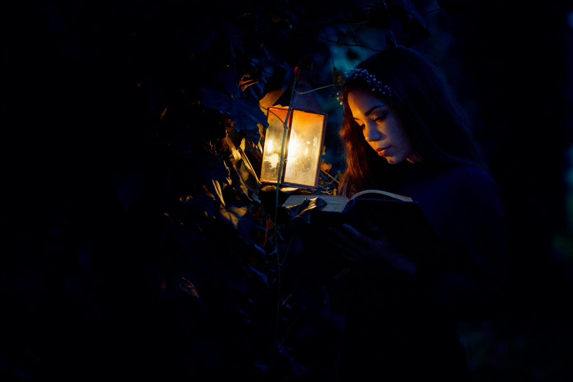 woman reading a book by a kerosene lamp