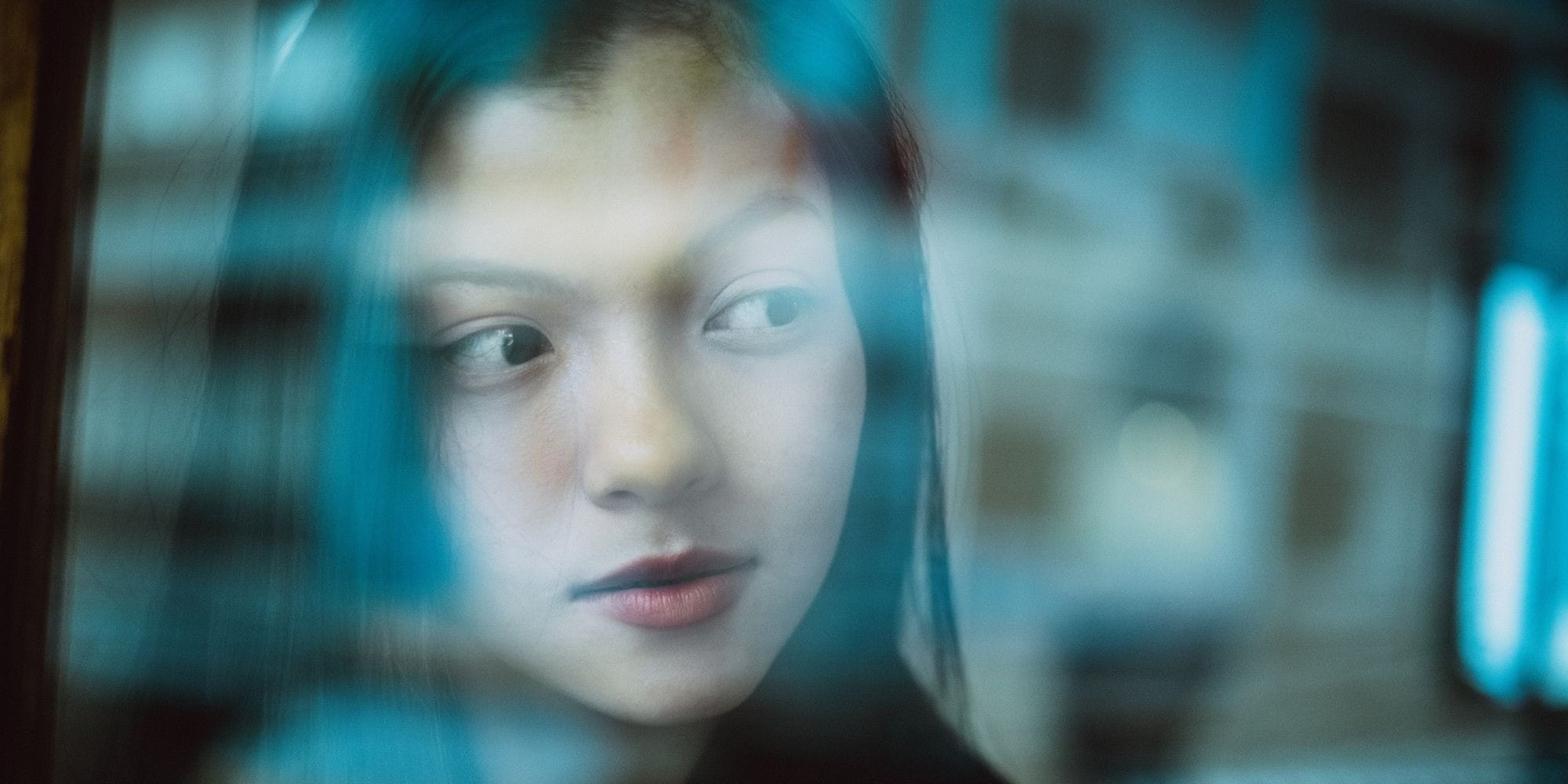 Asian woman with a dreamy look behind a glass wall