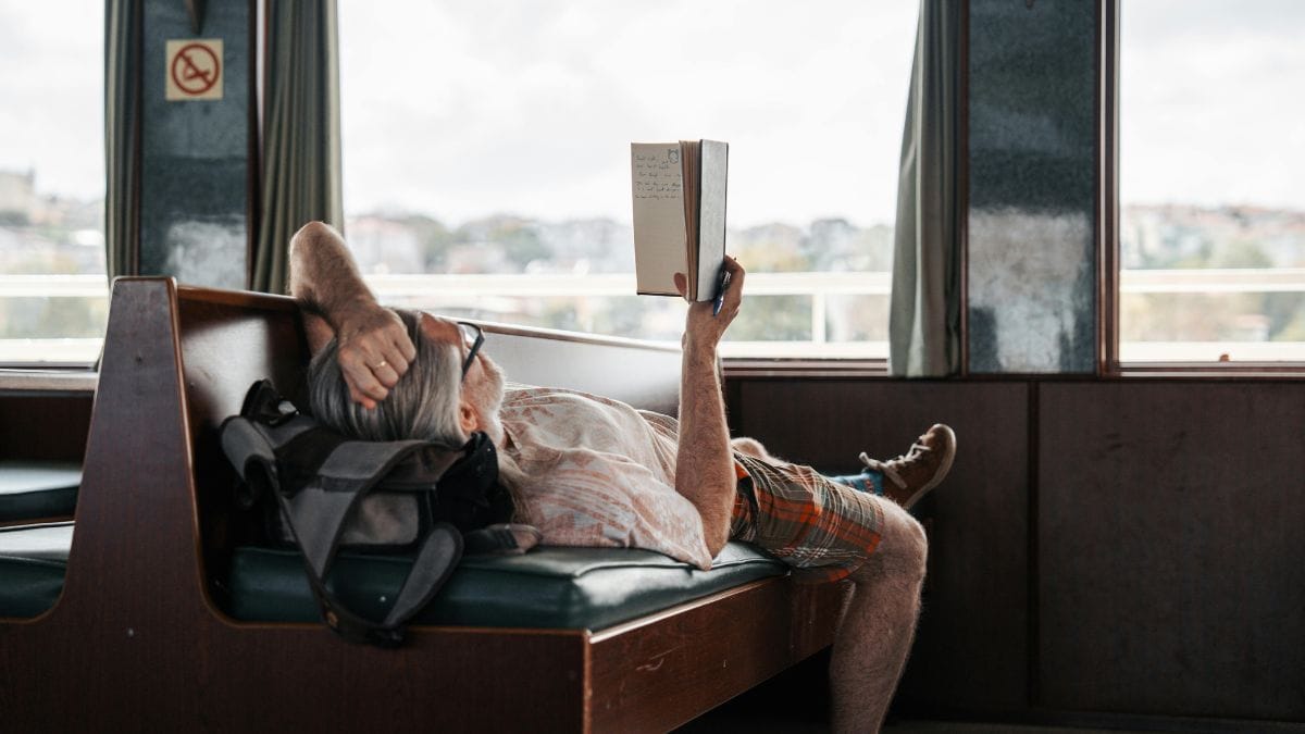 a man reading a book while lying on a train
