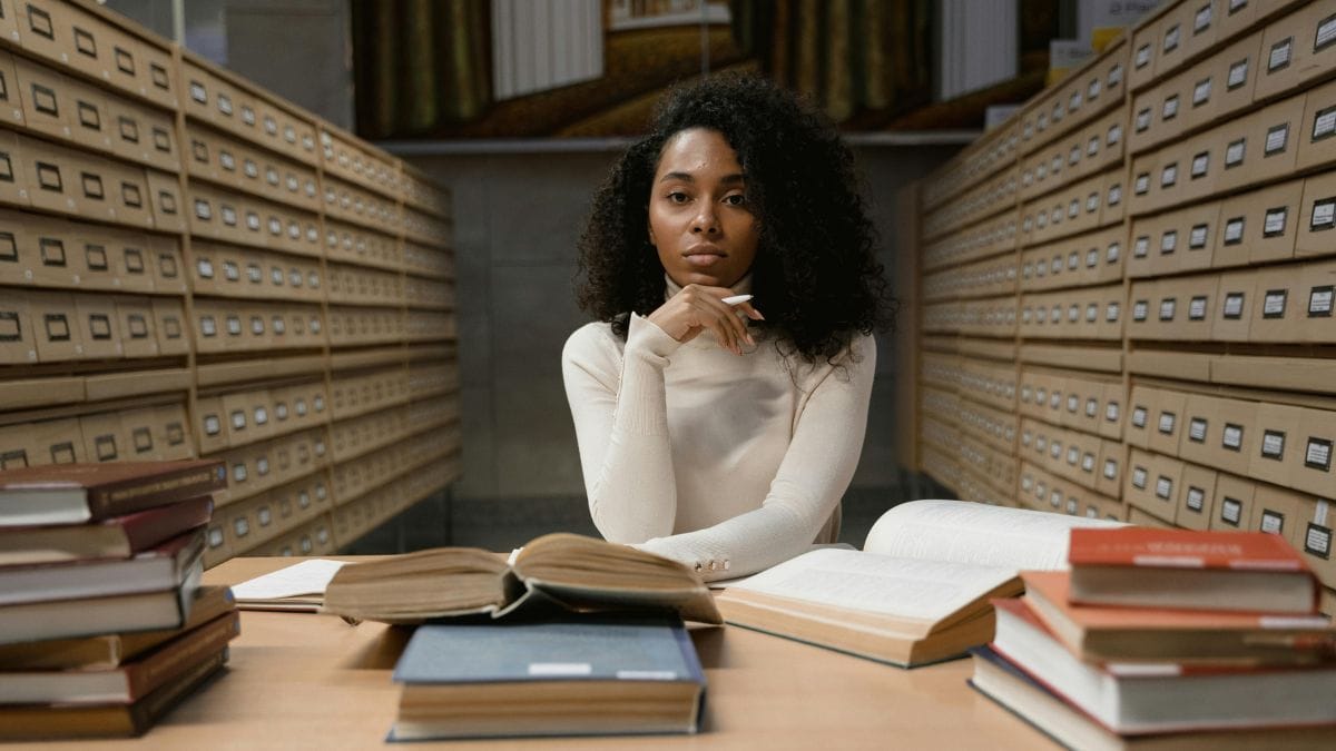 Woman with curly hair reading books in an archive
