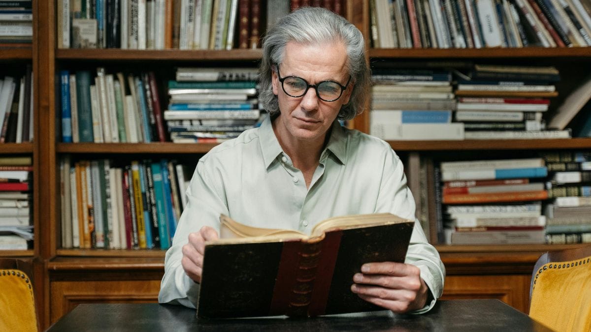 an elderly man sitting and reading an old book