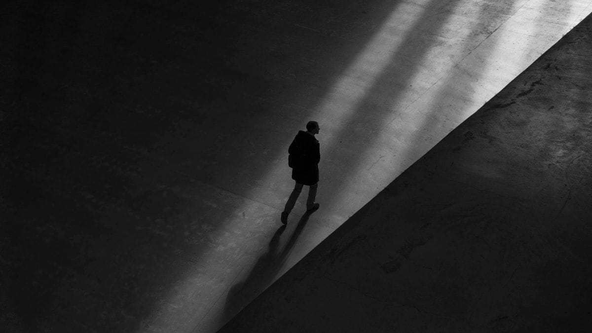 Person walking through light and shadow in a vast empty space