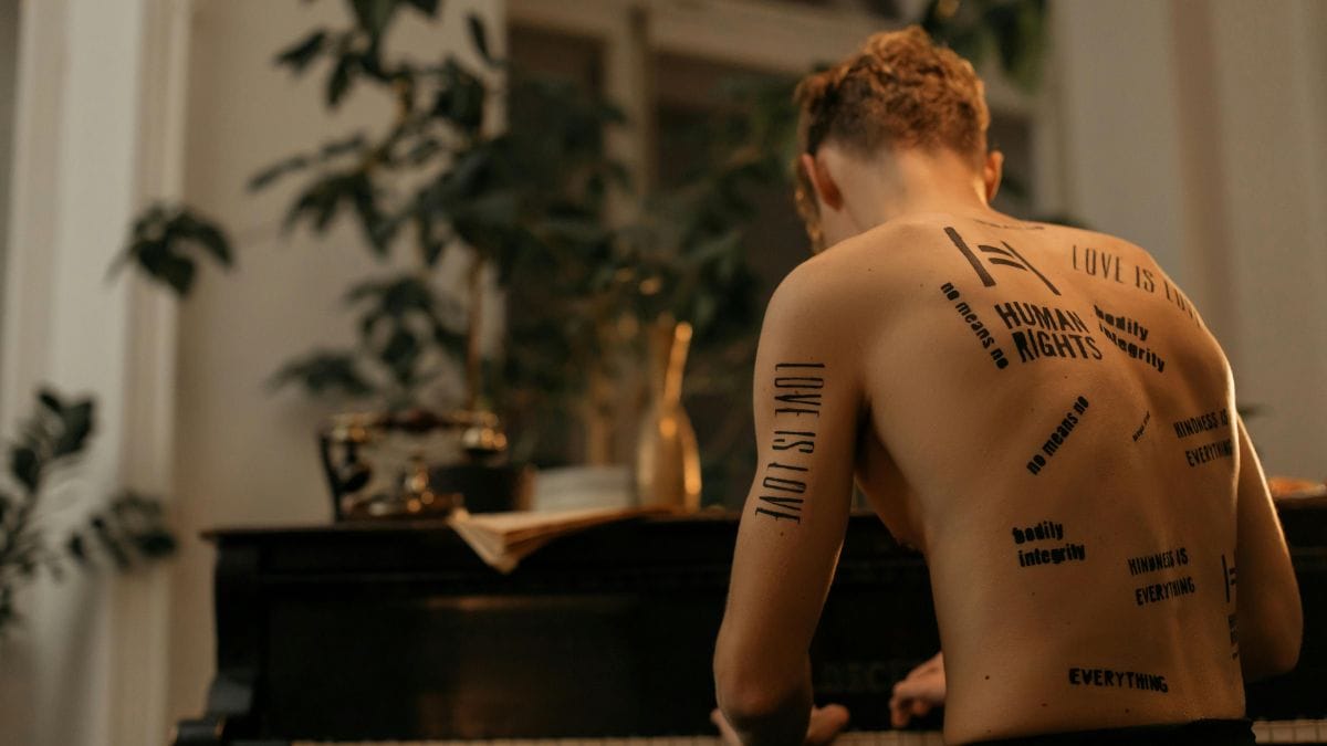 a man with tattoos on his back playing the piano