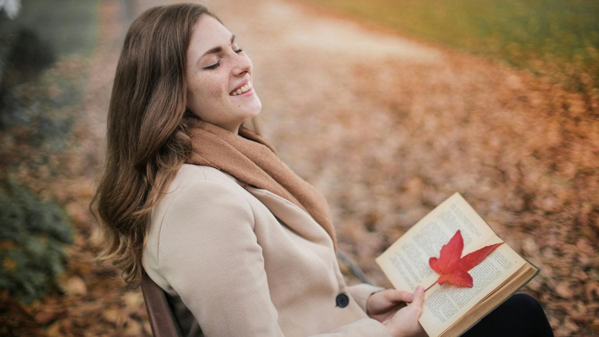 cheerful woman sitting in the park with a book