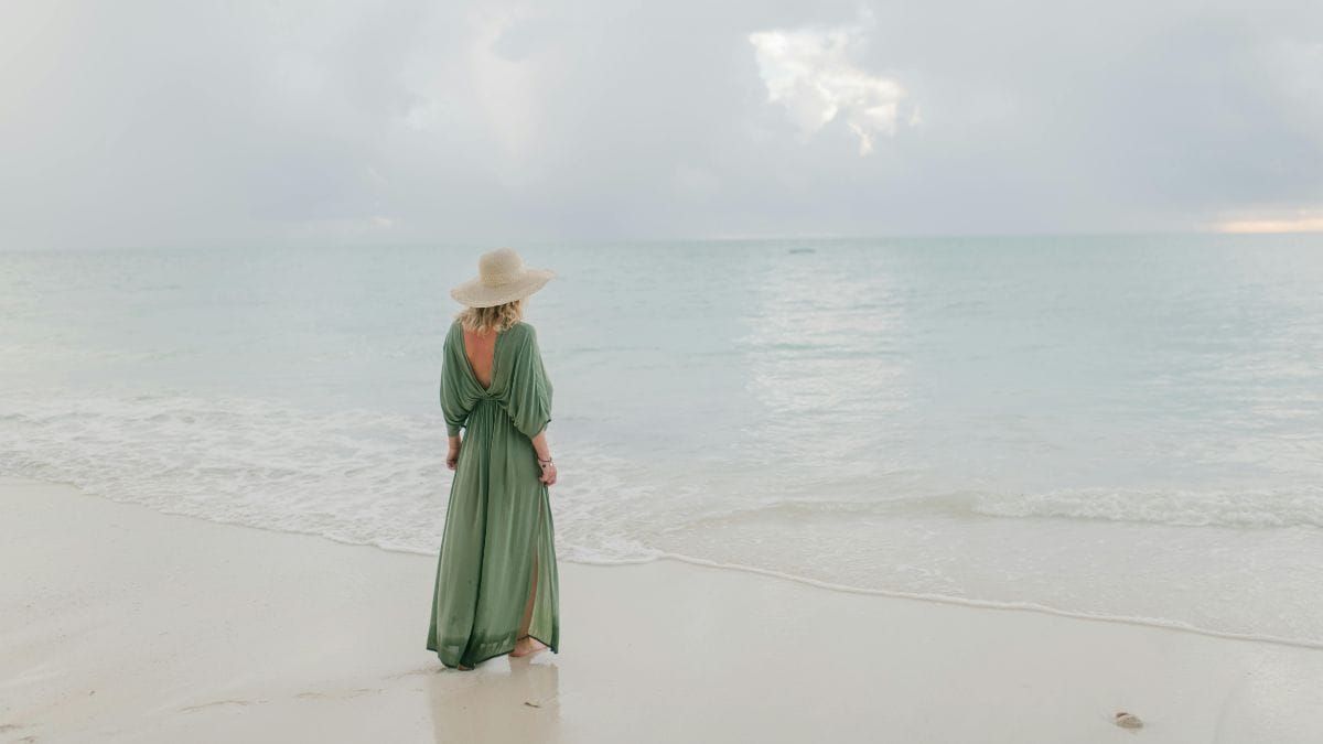 a woman in a hat looking far away towards the sea