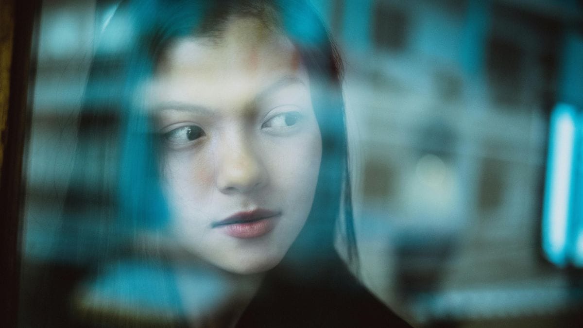 Asian woman with a dreamy look behind a glass wall