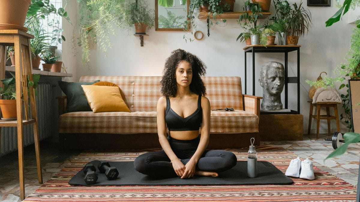 Woman sitting on a yoga mat in a cross-legged position to meditate