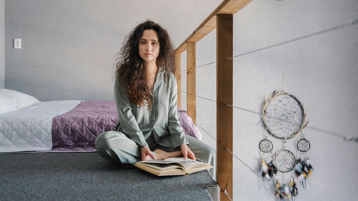 woman sitting cross-legged with a book in bed