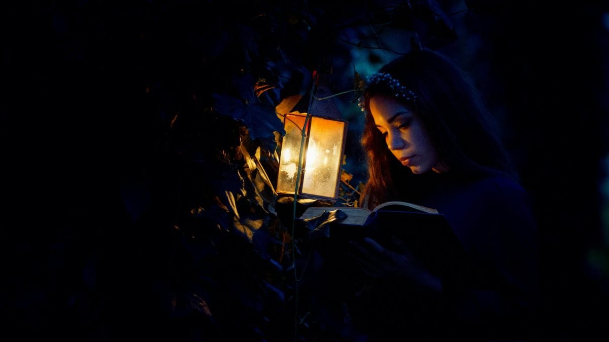 woman reading a book by a kerosene lamp