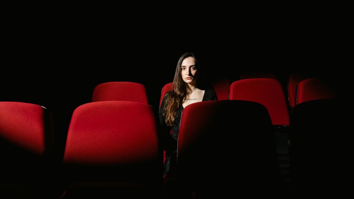 a woman sitting in the highlighted red chair in the dark
