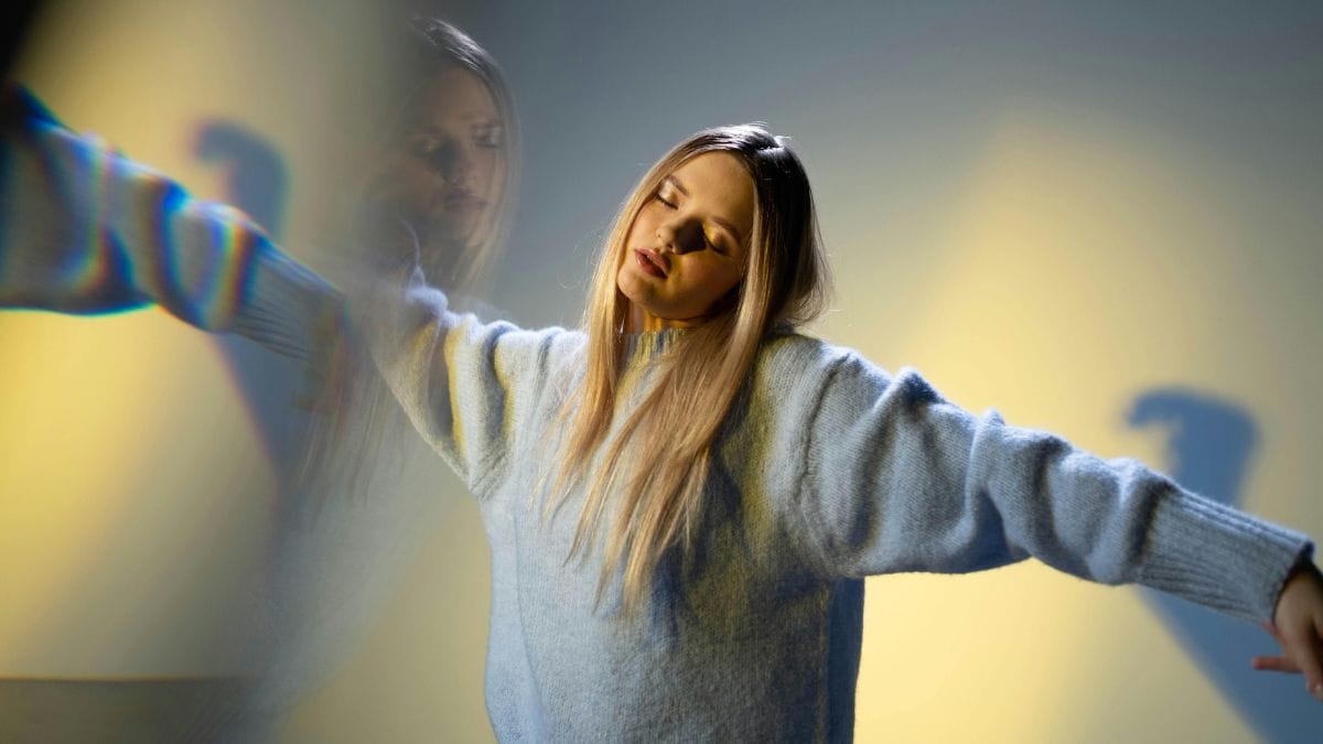 a woman in sweater with eyes closed and reflections and shadows around her