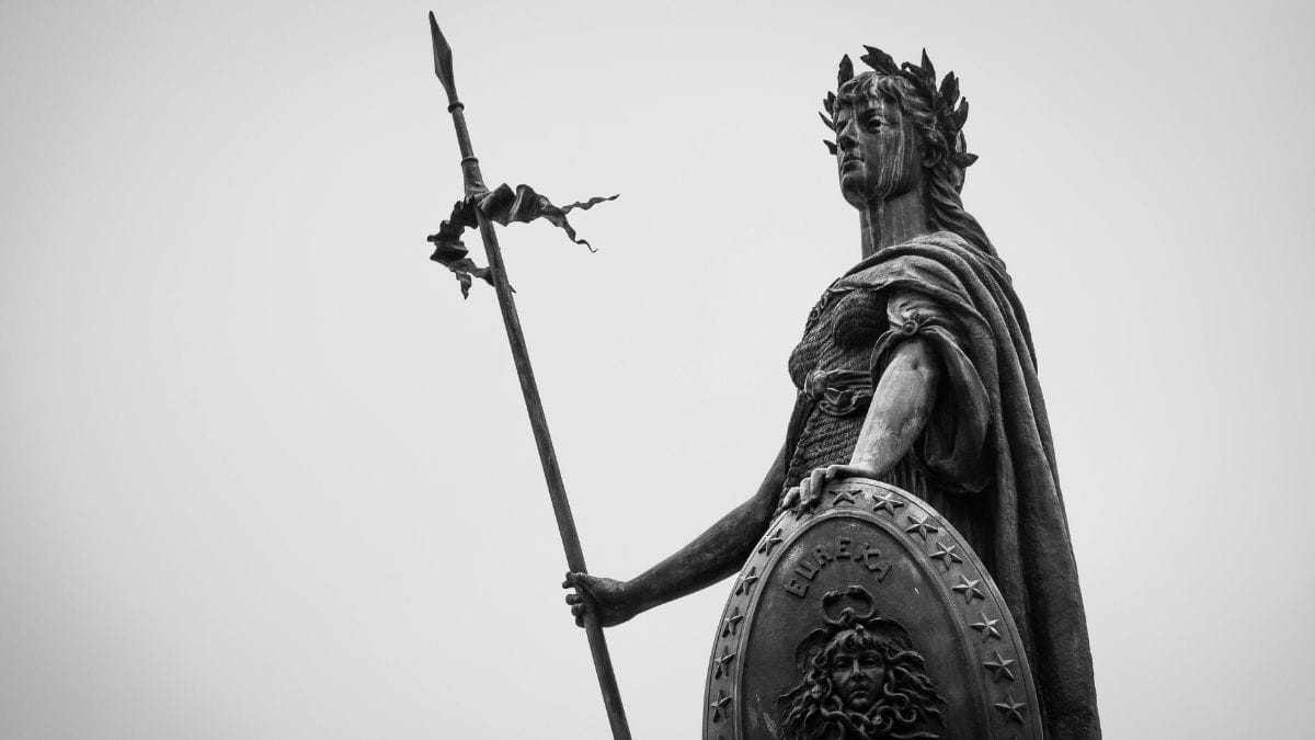 Classical statue of an ancient warrior holding a spear and shield, symbolizing timeless mythology and epic legends