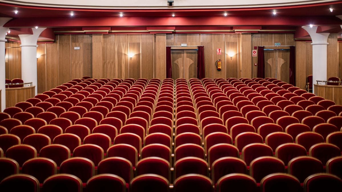 An empty theater with rows of red seats, photographed after the audience has left